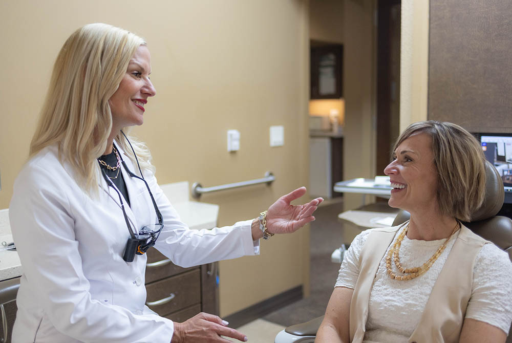 Dr. Jana Gyurina talks happily to a patient on the dental chair of Oak Park Dental
